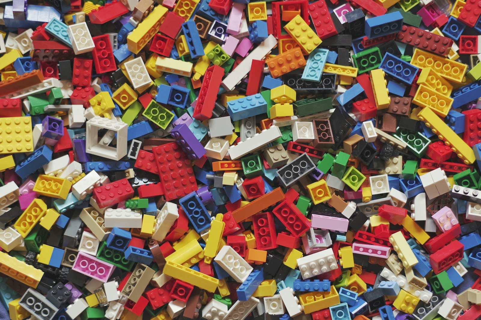 Pilha de blocos de Lego coloridos espalhados, base lúdica da arquitetura escolar